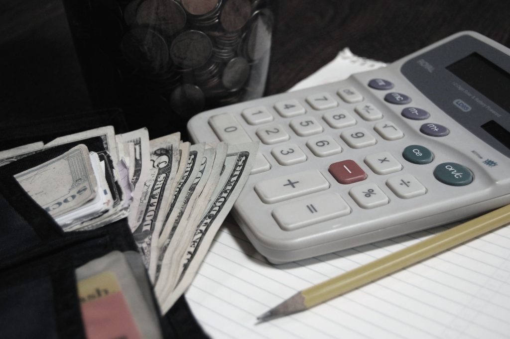 Photo of a calculator, a wallet with cash, and a savings jar of change depicting mortgage rate fluctuation and savings